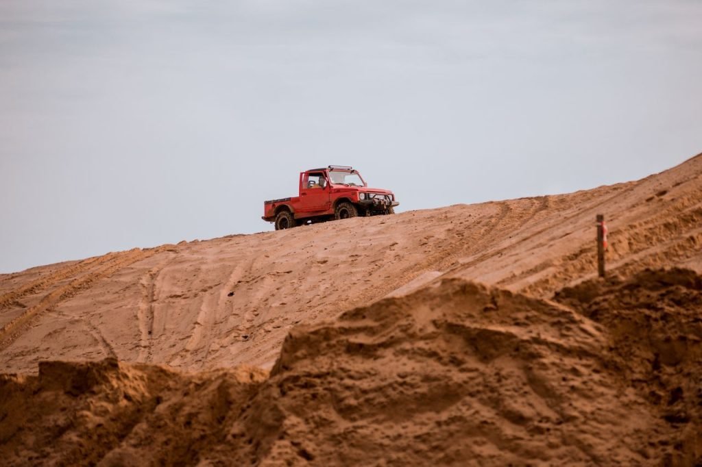 Red off-road vehicle navigating sandy dunes, capturing adventure and thrill in the Polish desert landscape.
